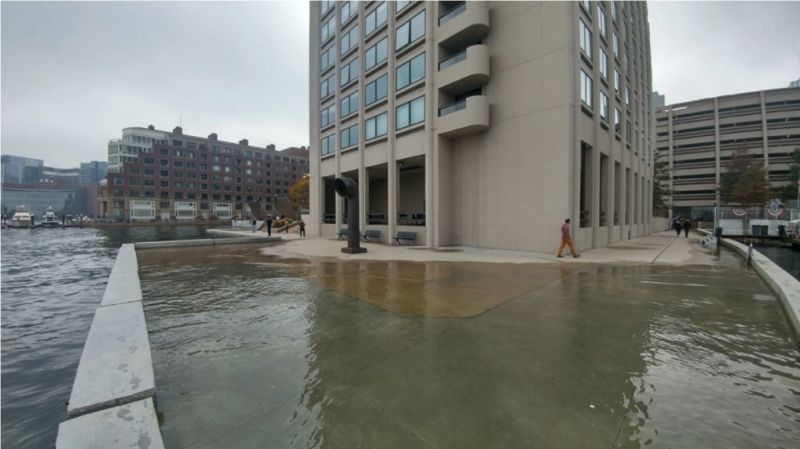 High tide flooding pushes water onto a walkway along the Boston waterfront near India Wharf in 2016