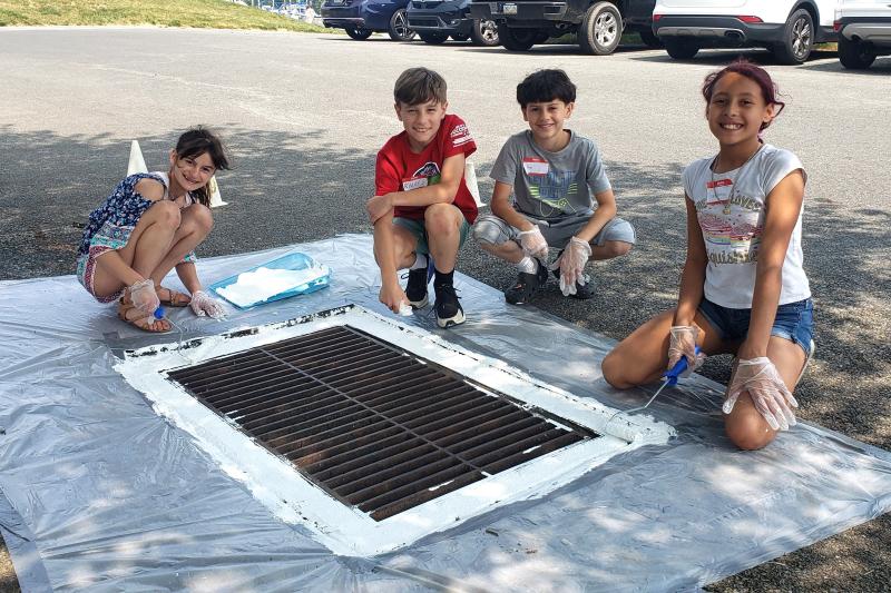 Hambright Elementary students paint a storm drain as part of their MWEE environmental action project.